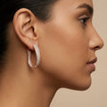 Boucles d'oreilles créoles ovales en or rose 18k pavées de pierres - bijou porté par une mannequin